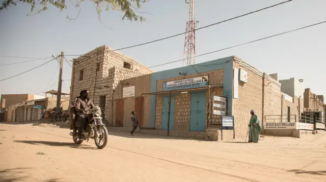 Rue de Tombouctou (Mali) avec des bâtiments en parpaings et une moto