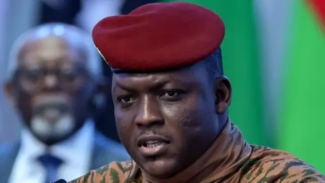 Portrait d'Ibrahim Traoré en tenue militaire beige avec un béret rouge, lors d'une interview