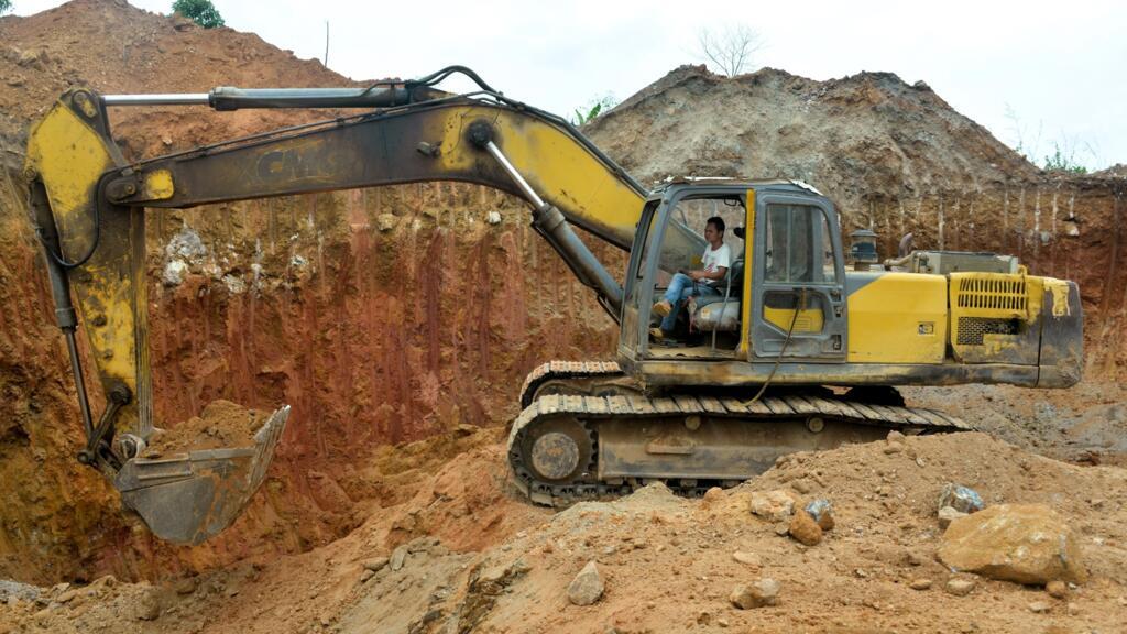 Sur cette photo prise le 4 avril 2018, un employé chinois d'une société minière conduit un bulldozer sur un site minier de la ville de Betare Oya, au Cameroun.