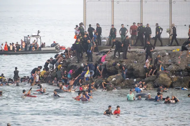 Foule de migrants traversant la frontière vers l'enclave espagnole de Ceuta, illustrant la crise migratoire de 2026.